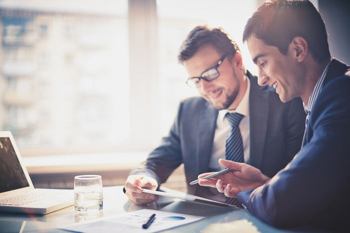two men smiling looking at notes