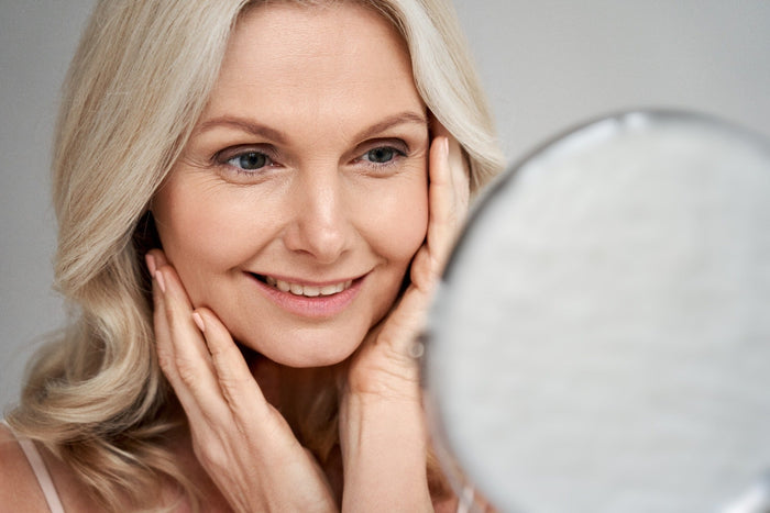 middle aged woman looking at her skin in mirror
